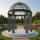 Decorative metal gazebo in a garden with flowers and trees