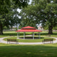 Red pavilion in a park with green grass and trees