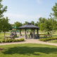 Hexagon two‑tier steel gazebo with stone columns, built‑in seating, and central firepit