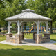 Gazebo with stone base in a park with playground equipment in the background