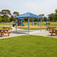 Three‑quarter view of square steel pavilion with blue roof and grey columns