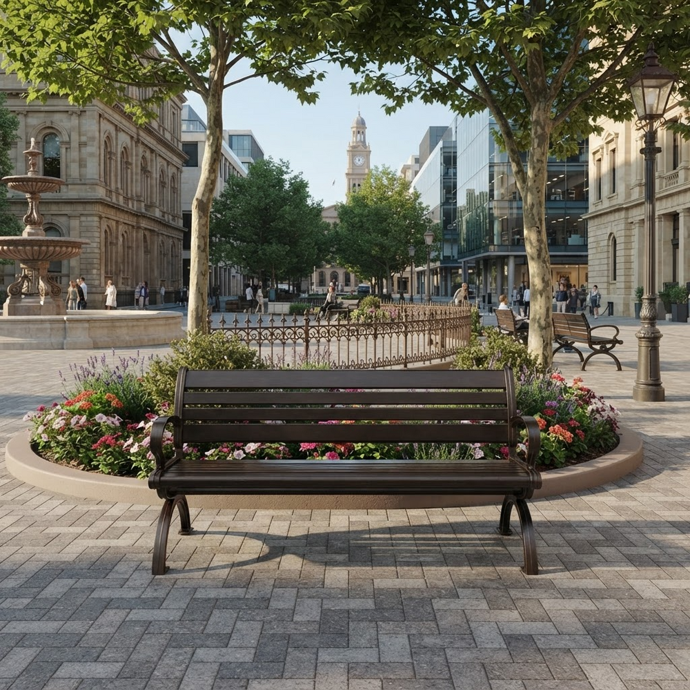 A dark brown wooden park bench is situated in a beautifully landscaped urban plaza with paved stone floors, flower beds, trees, and historic buildings in the background.