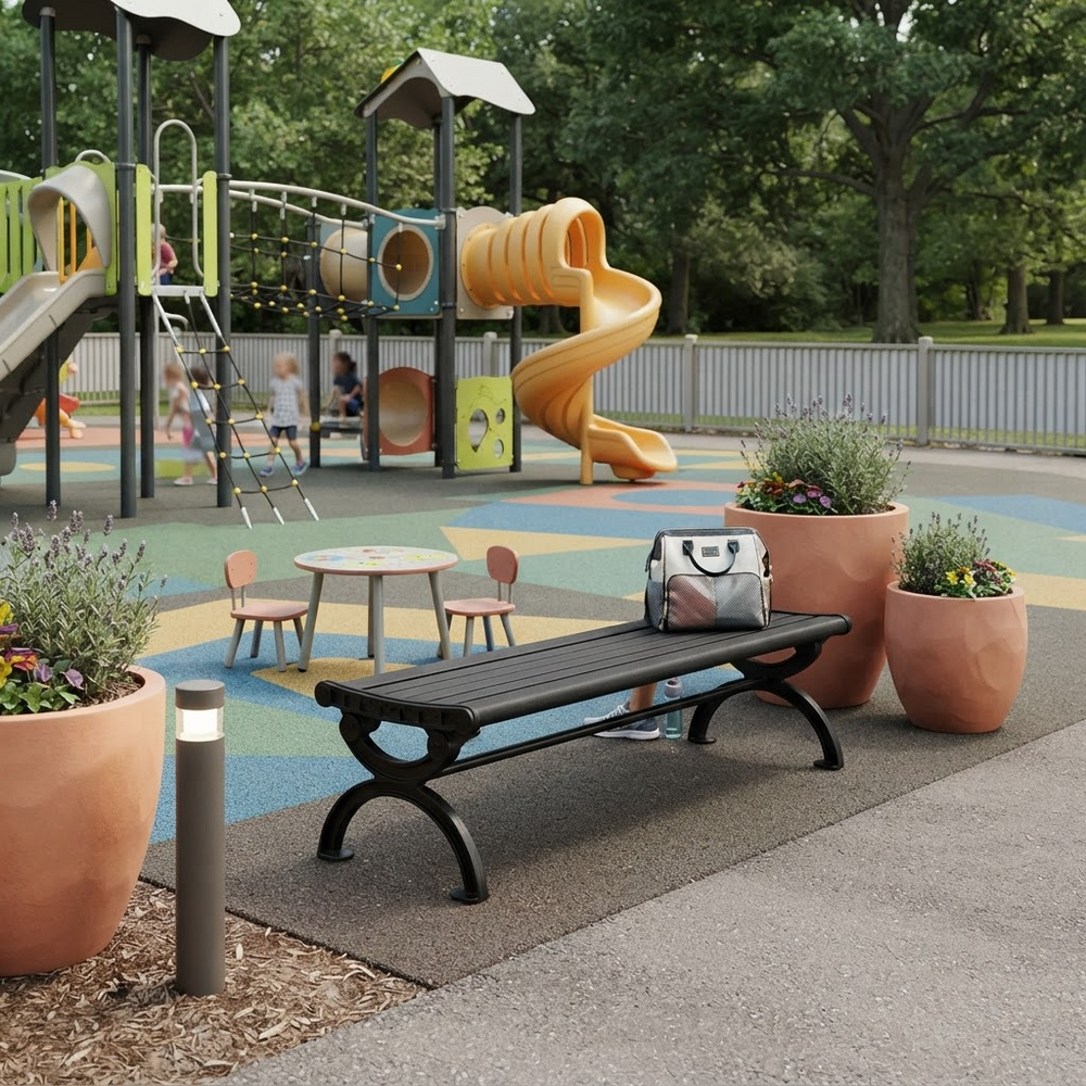 A black slatted park bench with curved legs sits in a playground setting, with a gray and white patterned bag resting on the backrest. The background features a colorful play structure, potted plants, and trees.