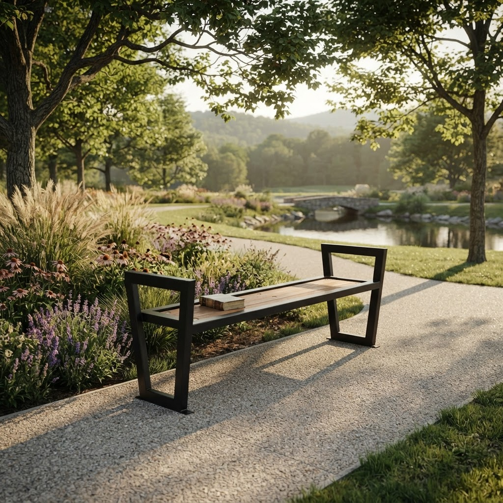 A modern outdoor bench with a dark metal frame and a light wood seat, placed on a gravel path in a landscaped park with trees, flowers, and a pond in the background.