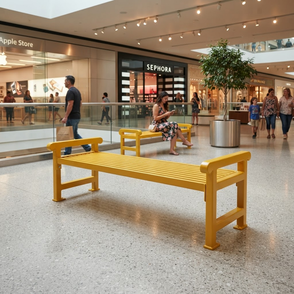 A bright yellow modern bench in a shopping mall, with a woman sitting on it and other shoppers walking in the background near Sephora and Apple Store storefronts.