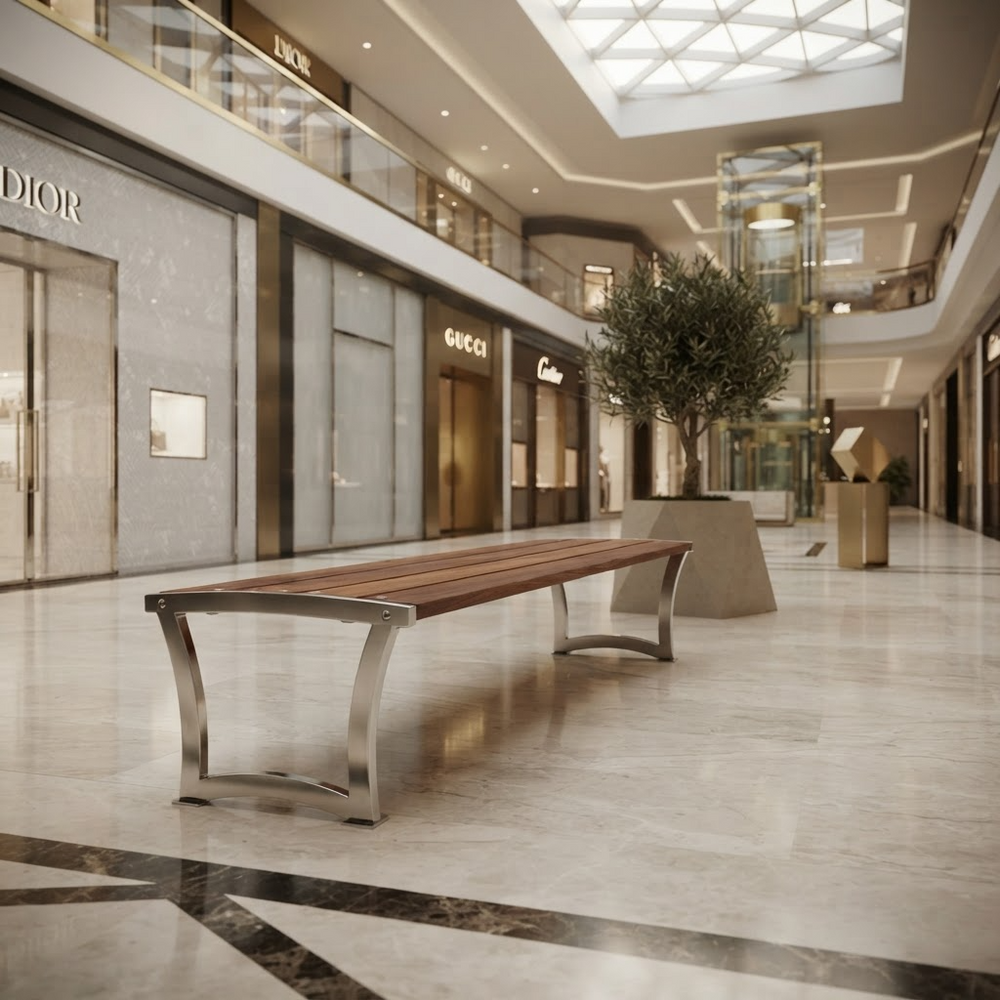 A modern wooden bench with curved stainless steel legs situated in a luxury, upscale shopping mall corridor with visible Dior, Gucci, and Cartier storefronts.