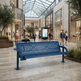 A blue slatted outdoor-style bench is placed in a modern shopping mall interior with visible people walking and sitting nearby, so this is a Lifestyle image rather than a clean Product/Packaging shot.