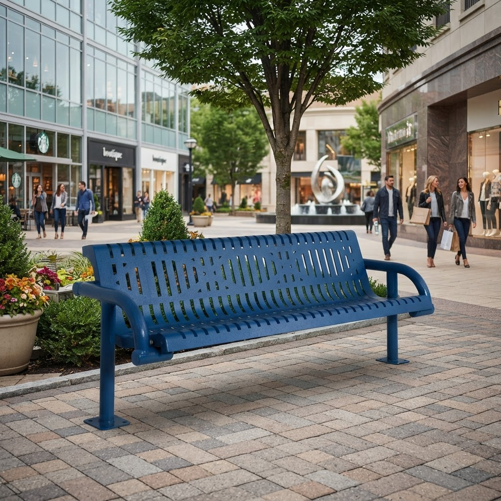 A blue metal park bench with a slatted back and seat, placed on a paved plaza in a city shopping district with pedestrians, trees, and storefronts in the background.