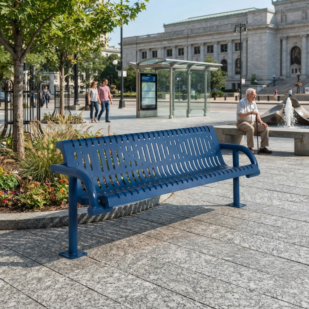 A blue metal park bench in an outdoor urban plaza, with a seated man on a bench nearby and a large stone building in the background.