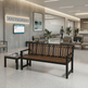 A modern wooden slat bench with a black metal frame sits in a spacious, contemporary office lobby. A matching small side table is positioned beside it.