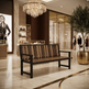 A modern wooden bench with a black metal frame and slatted back, positioned in a luxurious, upscale shopping mall interior with marble floors, a crystal chandelier, and a Dior store in the background.