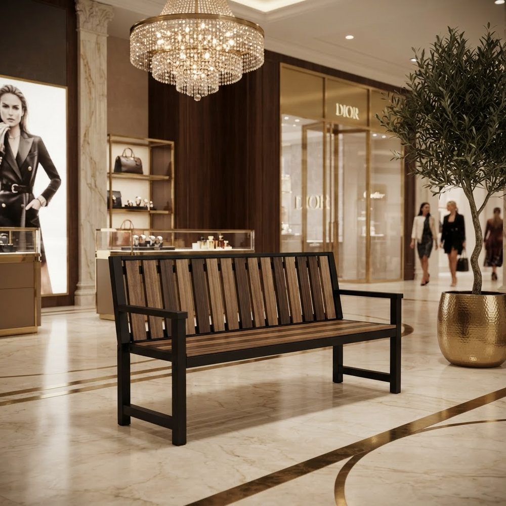 A modern wooden bench with a black metal frame and slatted back, positioned in a luxurious, upscale shopping mall interior with marble floors, a crystal chandelier, and a Dior store in the background.