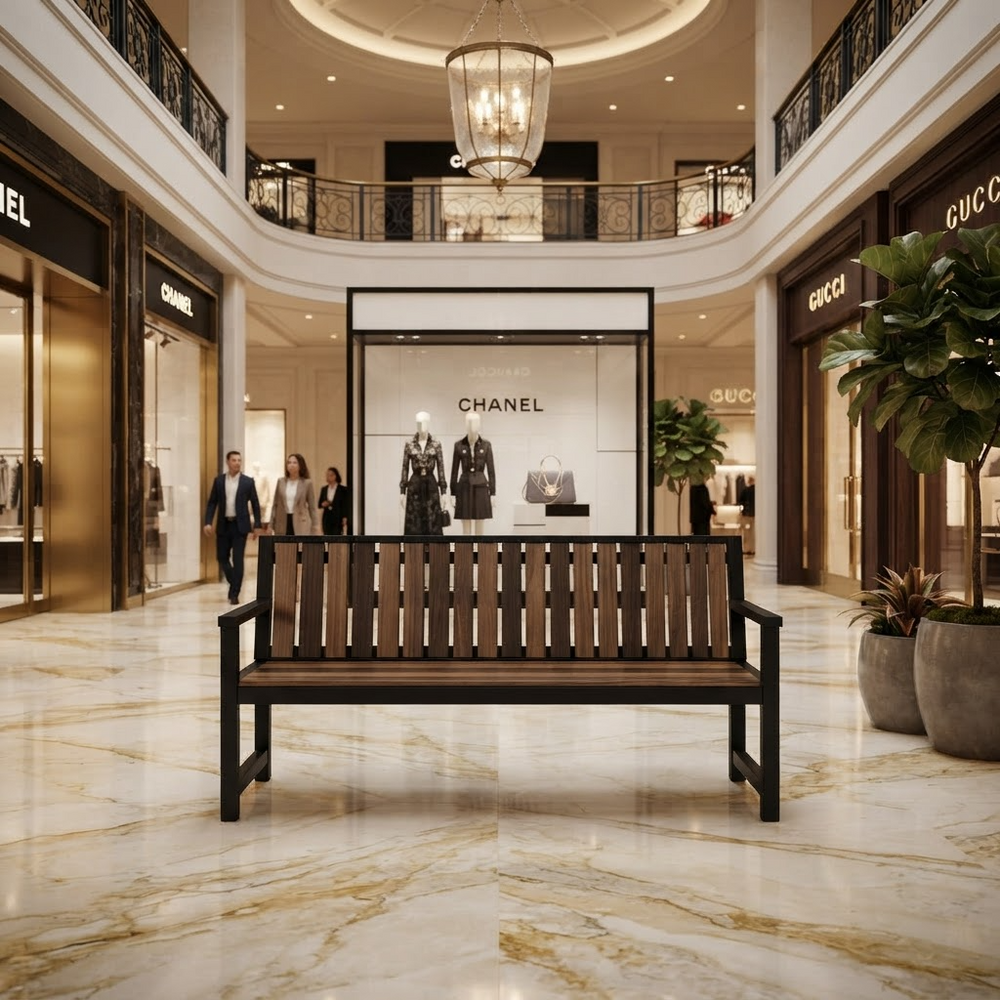 A modern wooden slat bench with a black metal frame sits in the center of a luxury shopping mall atrium with marble floors and visible Chanel and Gucci storefronts in the background.