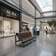 A modern wooden and metal bench sits in a spacious, contemporary indoor shopping mall atrium with a visible AURA Modern Living storefront. Several people are walking and standing in the background under a glass skylight.