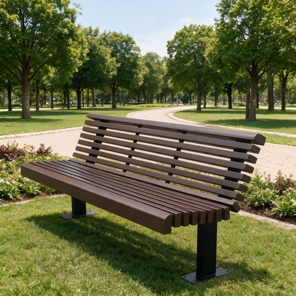 A modern outdoor park bench with dark brown slatted seating and backrest on black metal legs, situated on a green grassy lawn in a park with a winding path and trees in the background.