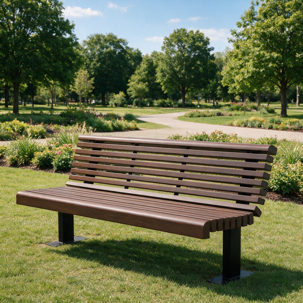 A modern outdoor park bench with brown slatted seating and backrests supported by black metal legs, situated on a green grassy lawn in a park with a winding path and trees in the background.