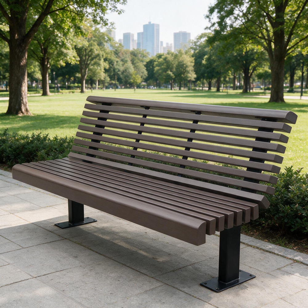 A modern park bench with brown slatted seating and backrests supported by black metal legs, situated on a paved path in a green park with trees and distant buildings.