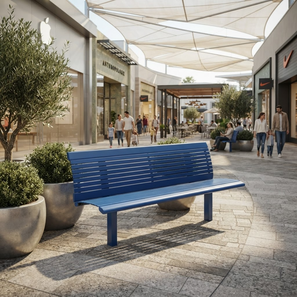 A modern blue slatted outdoor bench placed in a sunlit shopping plaza with potted plants, storefronts, and walking shoppers in the background.