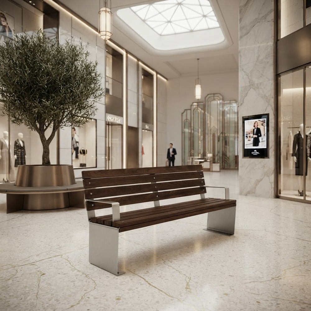 A modern wooden and metal bench placed in a luxury shopping mall interior with marble floors, glass storefronts, hanging lights, and a large potted tree in the background.