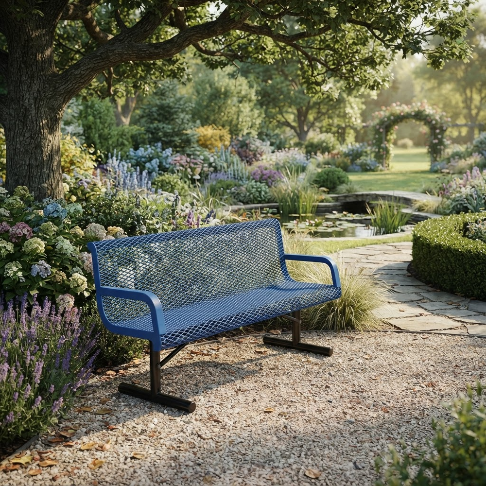 A blue metal mesh park bench with black legs, situated on a gravel path in a lush, sunlit garden with flowers, trees, and a stone pond in the background.