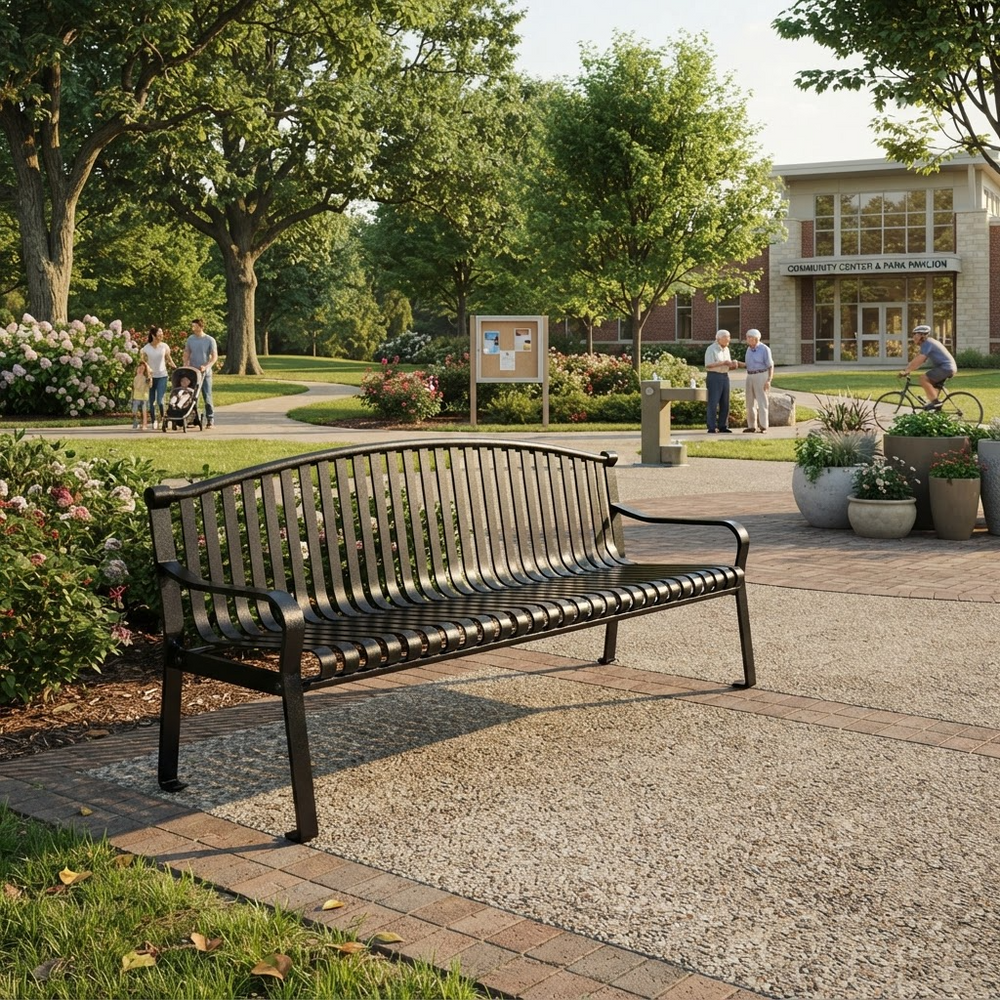 A black metal park bench with a slatted back and seat, placed on a paved walkway in a landscaped outdoor plaza with trees, people, and a building in the background.