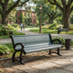 A modern park bench with a gray slatted seat and black curved arms and legs, situated on a stone path in a lush green park with trees, a historic brick building, and a few people in the background.