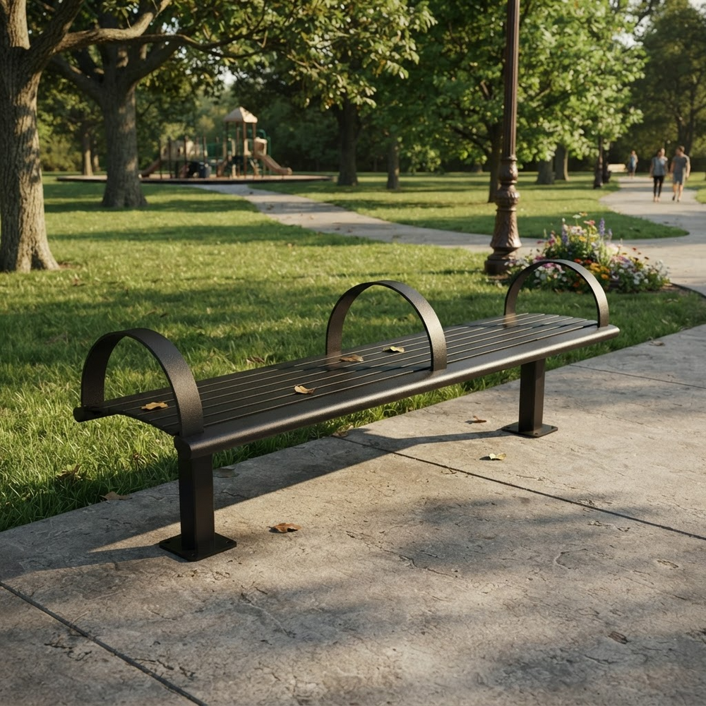 A dark metal park bench with curved backrests sits on a concrete sidewalk in a sunny park with green grass, trees, and a few distant people walking.