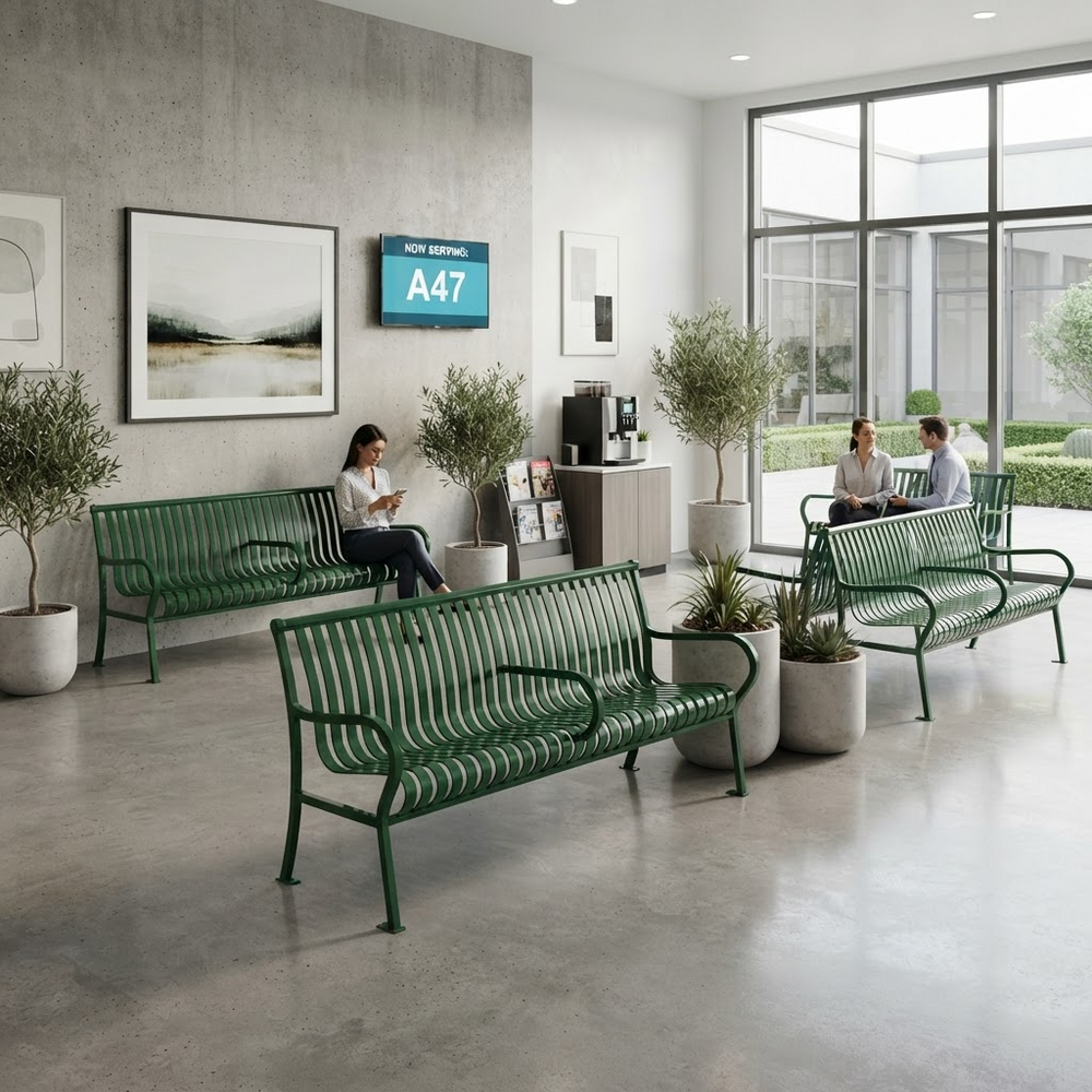 A modern indoor lobby scene with three green metal bench seating pieces arranged in a bright concrete-floored space. Two people are seated on the benches, and the environment includes framed wall art, potted trees, a small coffee station, and large windows.