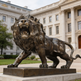 Dynamic bronze lion statue with open mouth, detailed teeth, and expressive muscular form