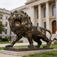 Bronze artwork of a lion in a fierce roaring stance, emphasizing strength and motion