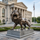 Sculpted bronze lion with open mouth and dynamic forward movement captured in metal.