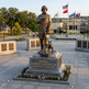 Bronze statue of General George S. Patton Jr. with a dog on a pedestal, surrounded by flags and plaques.