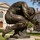 Abstract bronze figure in a fetal curl, showcasing defined muscles and sculptural texture.