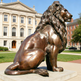 Bronze sculpture of a seated lion with a detailed mane and strong muscular body