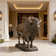 Bronze statue of a bison in front of a luxurious building entrance