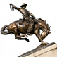 Cowboy and bucking horse bronze artwork featuring textured clothing, reins, and dynamic posture