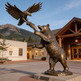 Bronze statue of a bear and an eagle in front of a building with mountains in the background
