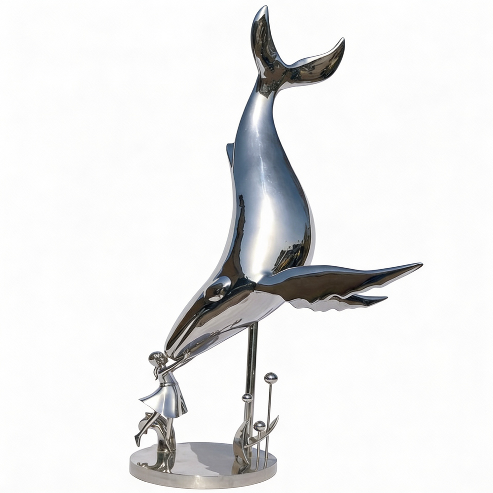 Polished metal sculpture of a whale diving toward a small human figure reaching upward
