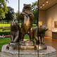Bronze bear statue outdoors and indoors, with a garden and museum setting.