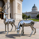 Metallic deer sculptures in front of a large building with a dome.
Contemporary chrome deer statues featuring a stag with antlers and a grazing doe