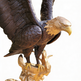 Decorative bronze eagle with open wings, perched on a stylized golden rocky surface