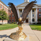 Sculpted bronze eagle in mid‑flight pose with detailed wings and golden terrain base