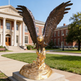 Bronze eagle statue capturing motion and strength, displayed on a polished golden base