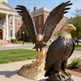 Bronze eagle statue capturing motion and strength, displayed on a polished golden base