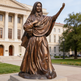 Bronze statue of a religious figure in front of a building
