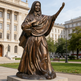 Bronze statue of a religious figure in front of a building
Sculpture of Mother Cabrini with realistic robe folds and serene expression