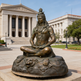 Bronze statue of a seated figure in front of a classical building
Bronze artwork depicting Shiva seated in meditation with symbolic elements