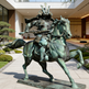 Bronze statue of a samurai on horseback in front of a modern building.
Metal statue of a samurai riding a horse in a dynamic pose