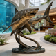 Bronze sculpture of a shark in an indoor setting with an aquarium in the background
Artistic bronze shark pair mounted on a stylized wave base