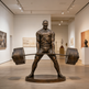 Bronze statue of a man lifting weights in an art gallery setting
Metal statue of a muscular lifter performing a deadlift on a circular base.